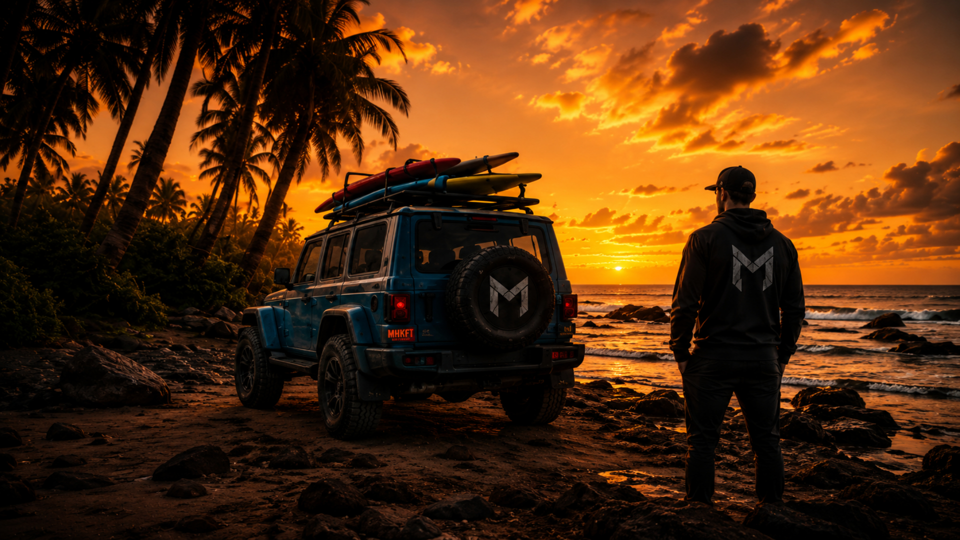 MHKFT overlanding 4x4 with surfboard and athlete in a branded hoodie on a beach at sunset